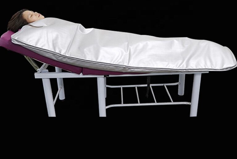 A bed with a sheet over it and a person laying on the side.